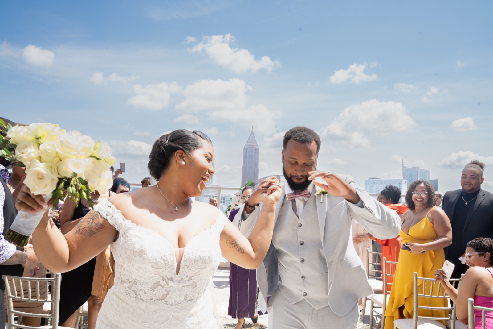 Couple celebrating walking down the aisle with Atlanta skyline — 2KNOT1 wedding photography
